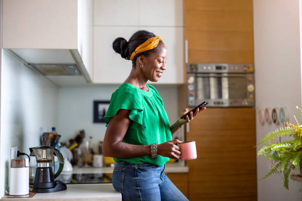 Mature woman using smartphone in the kitchen at home